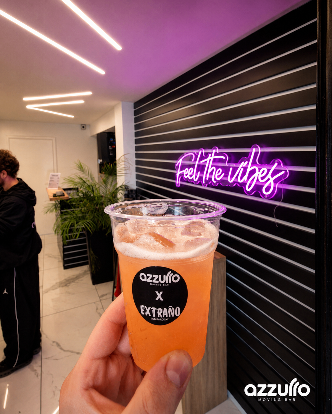 Azzurro Moving Bar branded cocktail in front of a neon sign